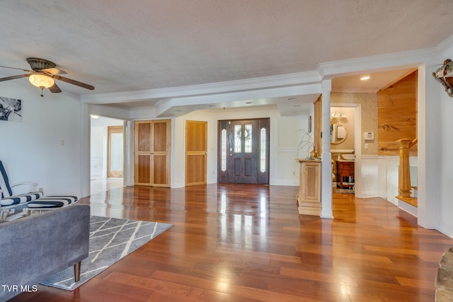 entryway featuring ornate columns, wood-type flooring, crown molding, and a textured ceiling