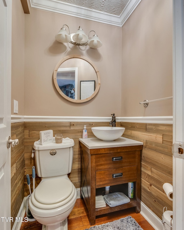 bathroom with ornamental molding, a textured ceiling, toilet, vanity, and hardwood / wood-style flooring