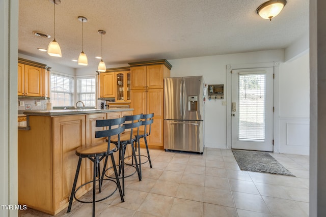 kitchen with pendant lighting, a textured ceiling, light tile patterned floors, and stainless steel fridge with ice dispenser