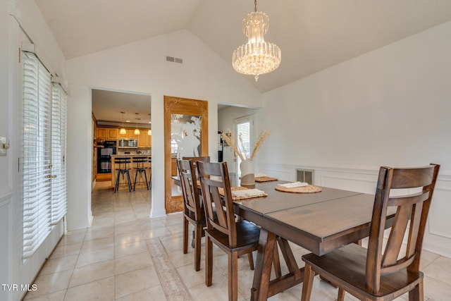 tiled dining space featuring high vaulted ceiling and an inviting chandelier