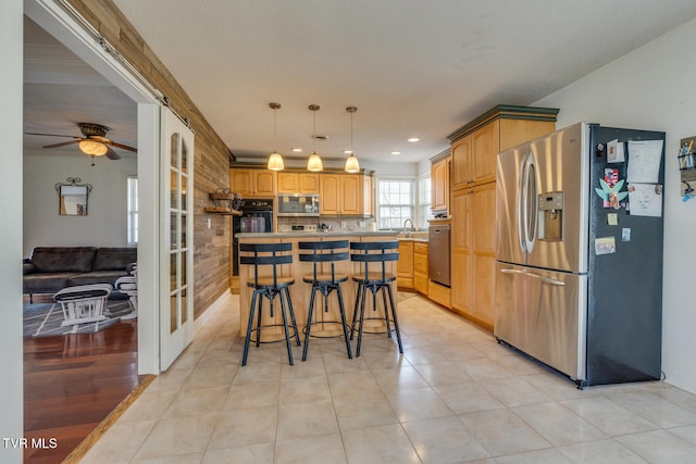 kitchen with appliances with stainless steel finishes, ceiling fan, sink, a kitchen island, and a breakfast bar area