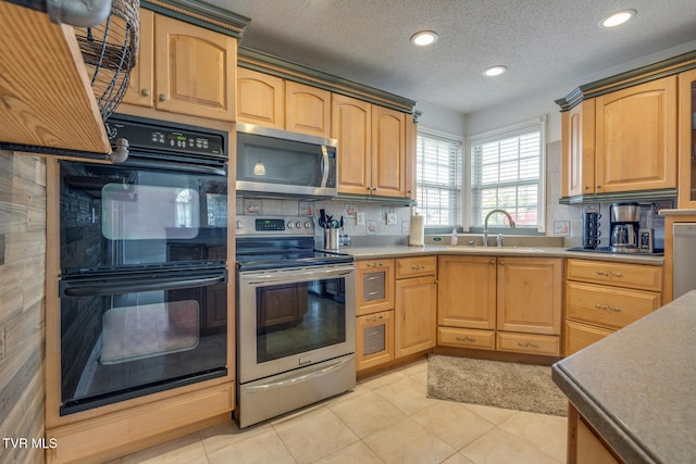 kitchen with sink, light tile patterned floors, stainless steel appliances, and a textured ceiling