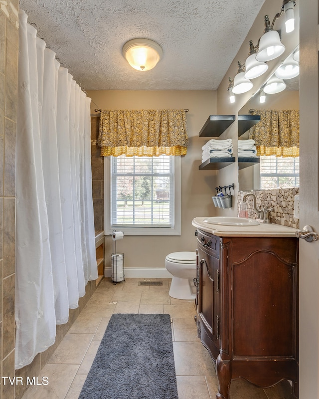 bathroom featuring vanity, toilet, a healthy amount of sunlight, and tile patterned floors