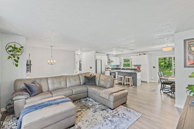 living room featuring light hardwood / wood-style flooring, a chandelier, and a textured ceiling