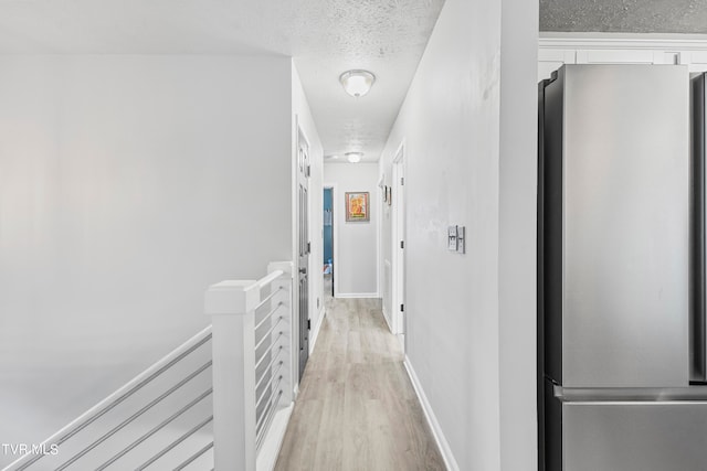 hall featuring a textured ceiling and light hardwood / wood-style flooring