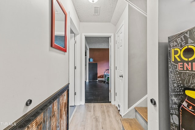 hallway featuring light hardwood / wood-style flooring and a textured ceiling