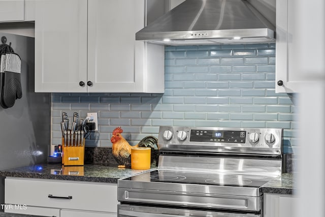 kitchen with stainless steel electric range oven, decorative backsplash, white cabinetry, and wall chimney exhaust hood