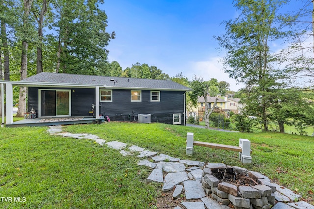 back of property with a lawn, central AC, and an outdoor fire pit