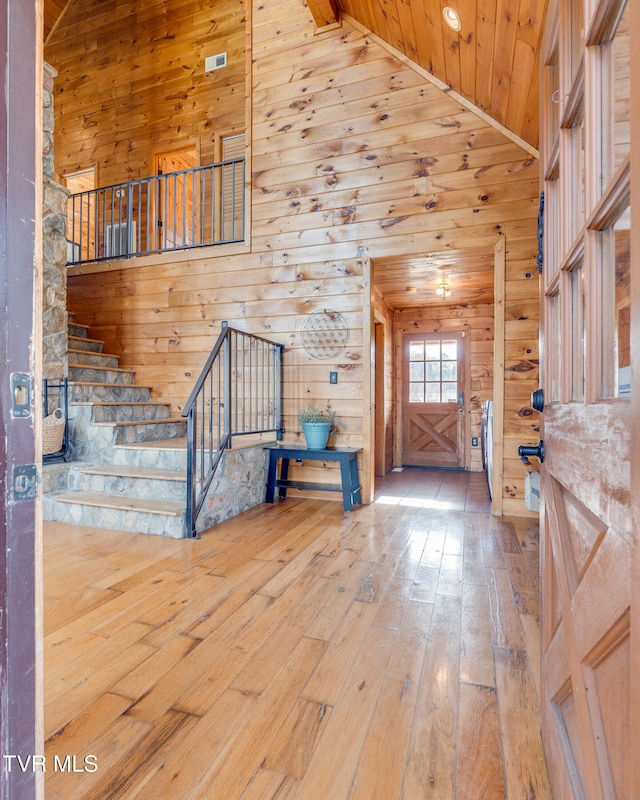 entrance foyer featuring wood-type flooring, high vaulted ceiling, wooden walls, and wood ceiling