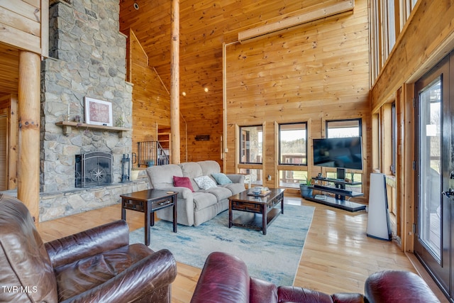 living room featuring a fireplace, light hardwood / wood-style flooring, high vaulted ceiling, and a healthy amount of sunlight