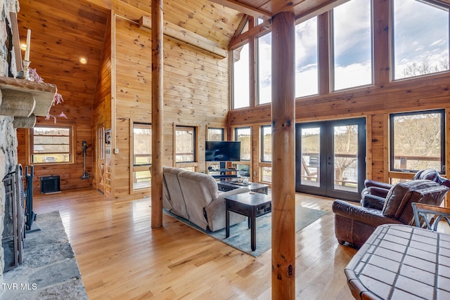 living room with light hardwood / wood-style floors, high vaulted ceiling, and french doors