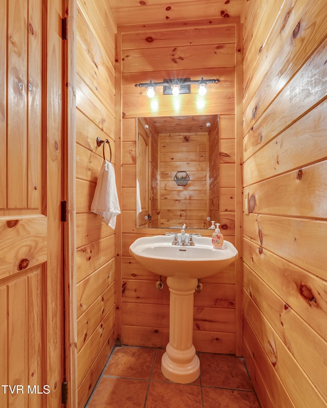 bathroom with tile patterned floors and wooden walls