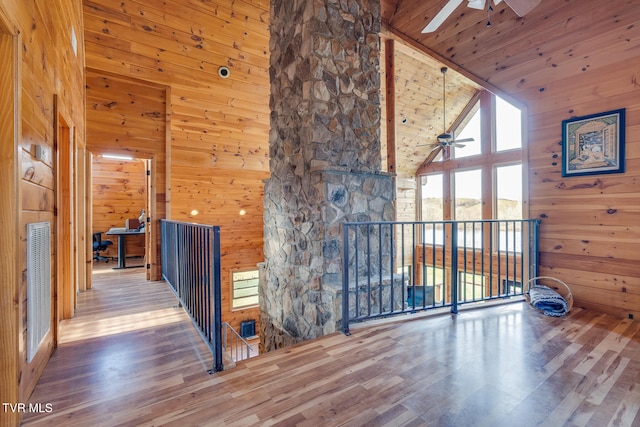 interior space with ceiling fan, wooden walls, high vaulted ceiling, and wood-type flooring