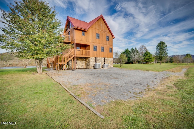 exterior space featuring central AC, a wooden deck, and a lawn