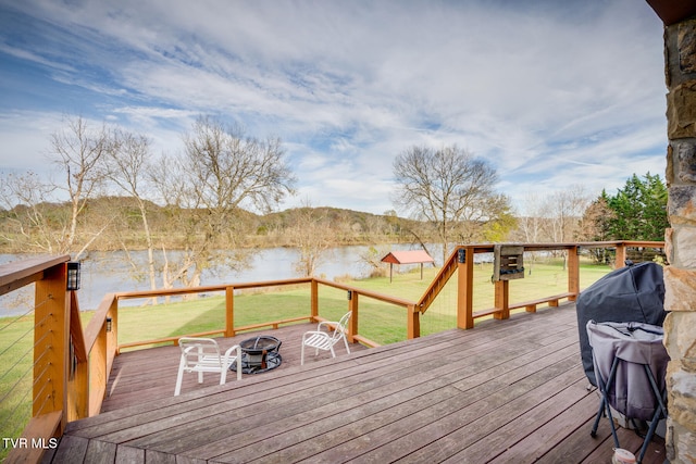 deck with a lawn, a water view, and an outdoor fire pit