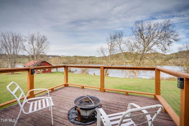 wooden terrace featuring a water view, a fire pit, and a lawn