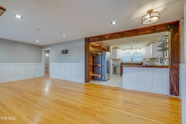 unfurnished living room with beamed ceiling and light hardwood / wood-style flooring