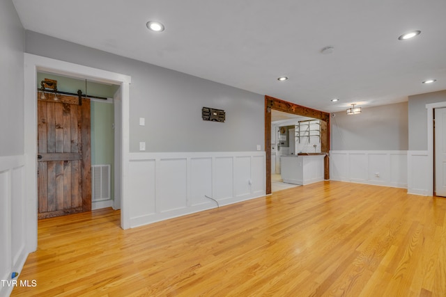 empty room featuring a barn door and light hardwood / wood-style flooring