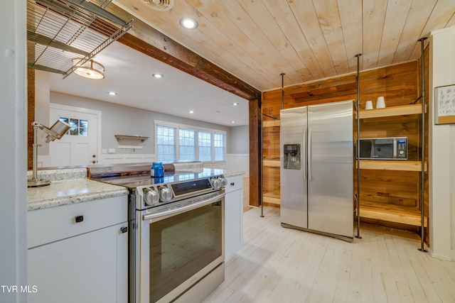 kitchen with white cabinets, stainless steel appliances, light hardwood / wood-style flooring, and light stone counters