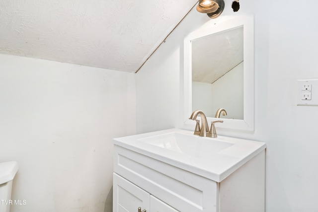 bathroom featuring vanity, a textured ceiling, and vaulted ceiling