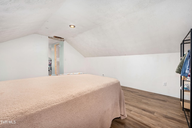 bedroom featuring a textured ceiling, hardwood / wood-style floors, and vaulted ceiling