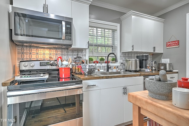 kitchen with backsplash, sink, ornamental molding, white cabinetry, and stainless steel appliances