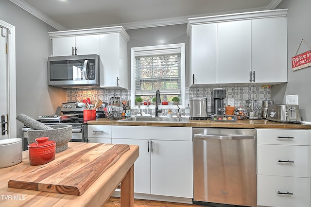 kitchen featuring white cabinets, crown molding, sink, and appliances with stainless steel finishes