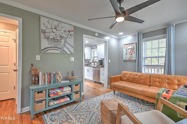 living room with crown molding, light hardwood / wood-style flooring, ceiling fan, and sink