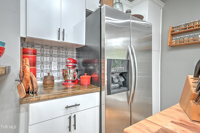 kitchen featuring white cabinets, stainless steel fridge, tasteful backsplash, and dark stone countertops