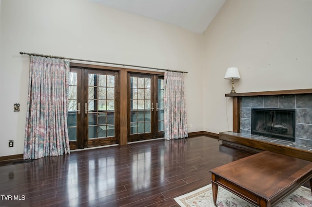 living room featuring a tiled fireplace, french doors, high vaulted ceiling, and dark wood-type flooring