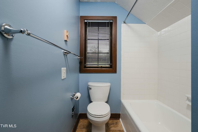 bathroom with a textured ceiling, bathtub / shower combination, vaulted ceiling, and toilet