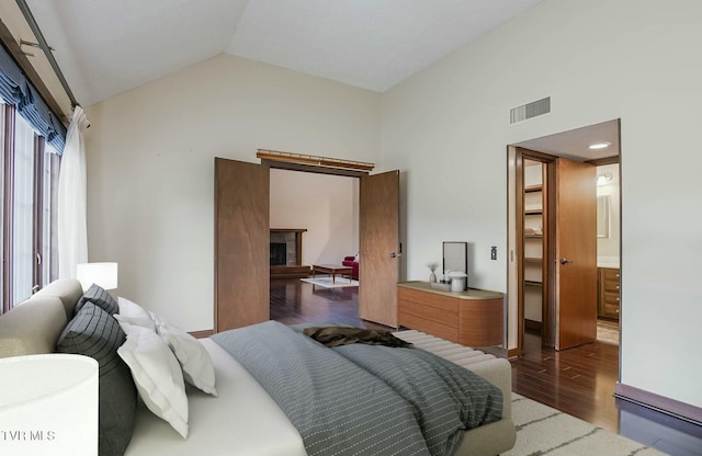 bedroom featuring a spacious closet, hardwood / wood-style floors, connected bathroom, a closet, and lofted ceiling