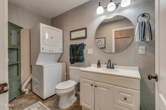 bathroom featuring vanity, toilet, and stacked washer and dryer