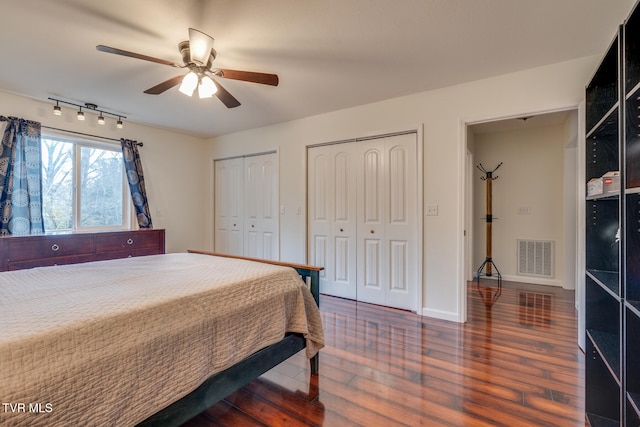 bedroom with ceiling fan, dark wood-type flooring, and multiple closets