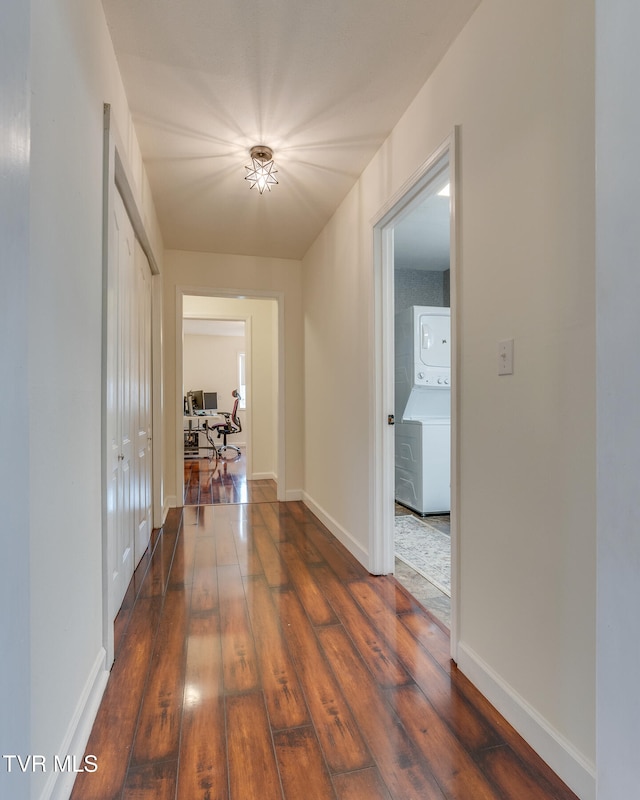 corridor with dark hardwood / wood-style floors and stacked washing maching and dryer