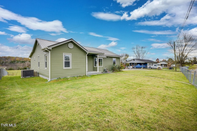 rear view of property featuring a yard and cooling unit