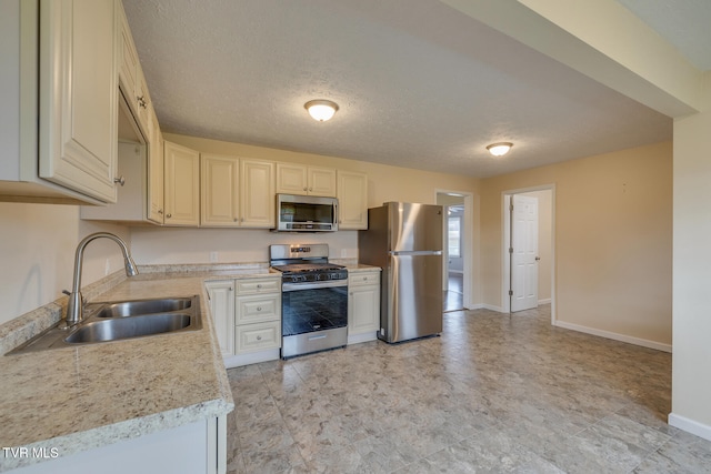 kitchen with appliances with stainless steel finishes, a textured ceiling, and sink