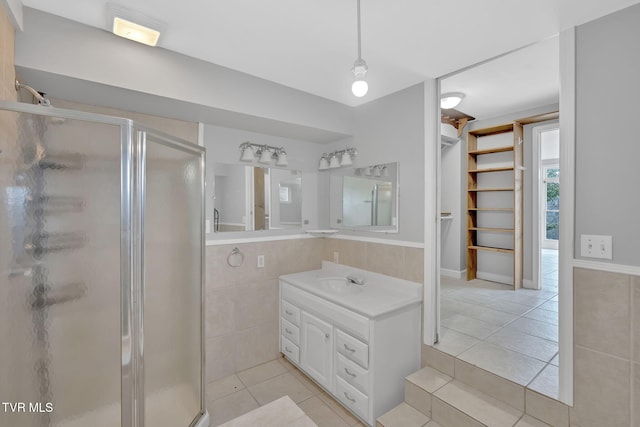 bathroom with tile patterned floors, tile walls, vanity, and an enclosed shower