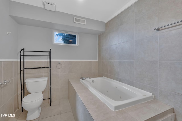 bathroom with tile patterned floors, a bathing tub, tile walls, and toilet