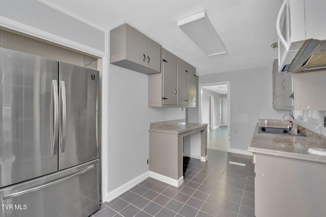 kitchen with dark tile patterned flooring, stainless steel fridge, and sink