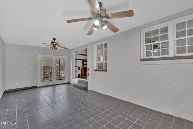 tiled spare room featuring ceiling fan and french doors