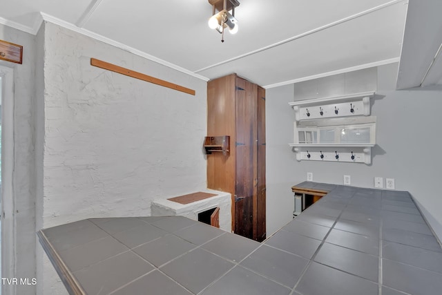 kitchen with tile countertops, white cabinetry, and ornamental molding