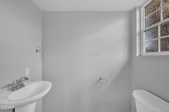 bathroom with toilet, a healthy amount of sunlight, and sink