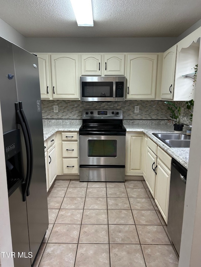 152 Gray Station Rd Unit 18, Gray, TN 37615 - kitchen featuring appliances with stainless steel finishes, tasteful backsplash, light tile patterned floors, a textured ceiling, and cream cabinetry