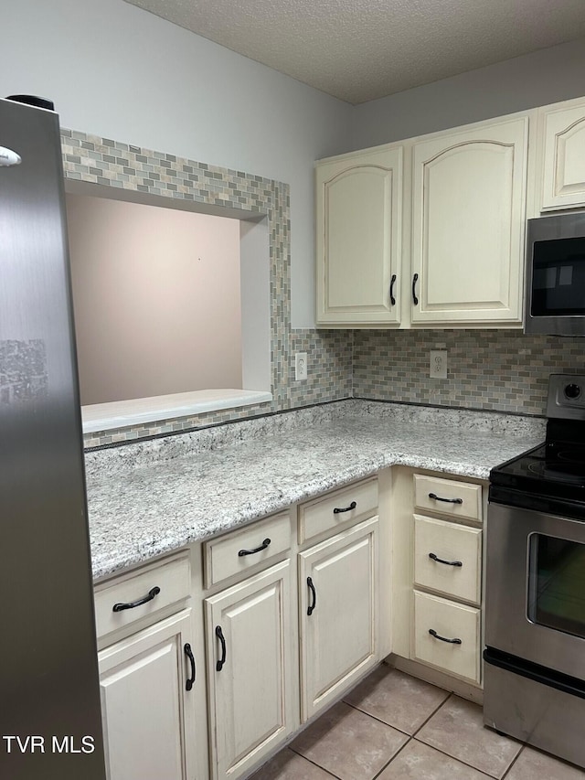 kitchen with tasteful backsplash, light stone countertops, light tile patterned floors, and appliances with stainless steel finishes