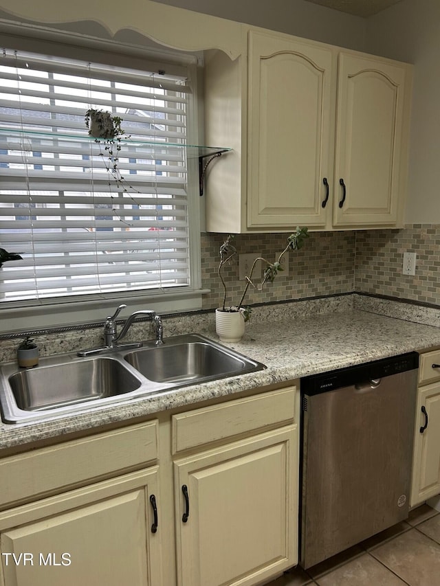 kitchen with dishwasher, backsplash, sink, cream cabinetry, and light tile patterned flooring