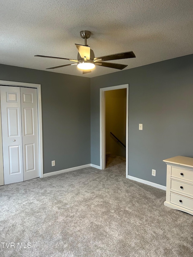 unfurnished bedroom featuring light carpet, a textured ceiling, a closet, and ceiling fan