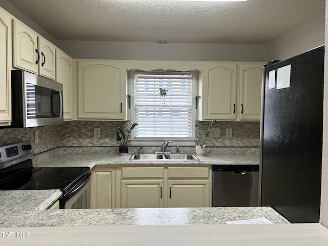 kitchen featuring appliances with stainless steel finishes, backsplash, cream cabinets, and sink