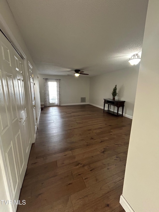 interior space featuring ceiling fan, dark wood-type flooring, and a textured ceiling