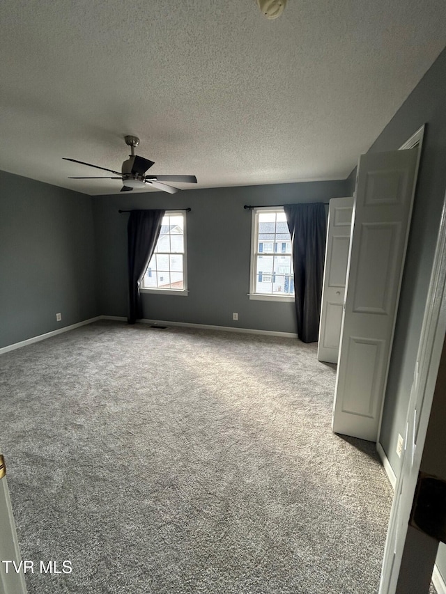 carpeted empty room featuring ceiling fan and a textured ceiling